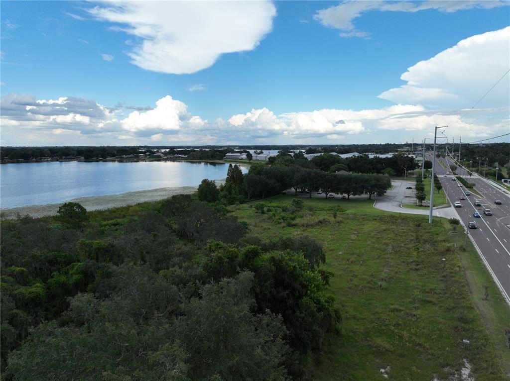 An aerial view shows a grassy lot next to a lake and a multi-lane road — 0 S HAVENDALE BOULEVARD NW, WINTER HAVEN, FL