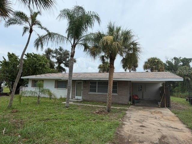 A single-story house with a carport and palm trees sits on a grassy lot — 1604 BAYSHORE ROAD, NOKOMIS, FL