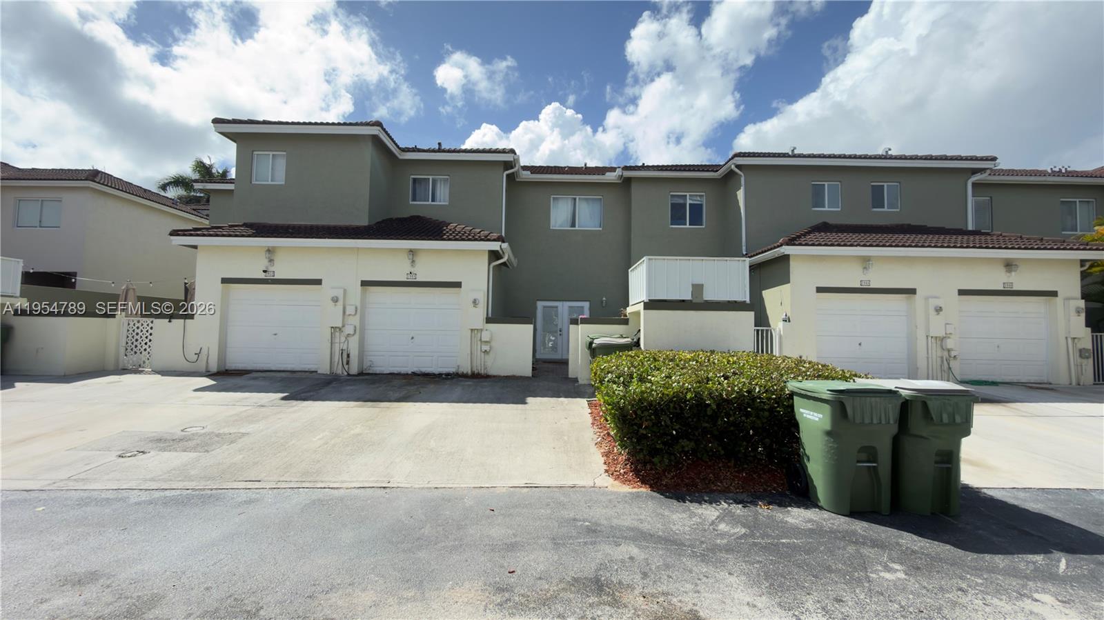 The exterior view shows a multi-unit townhouse complex with garages and a paved driveway — 1948 SE 24th Ave, Homestead FL 33035, HOMESTEAD, FL
