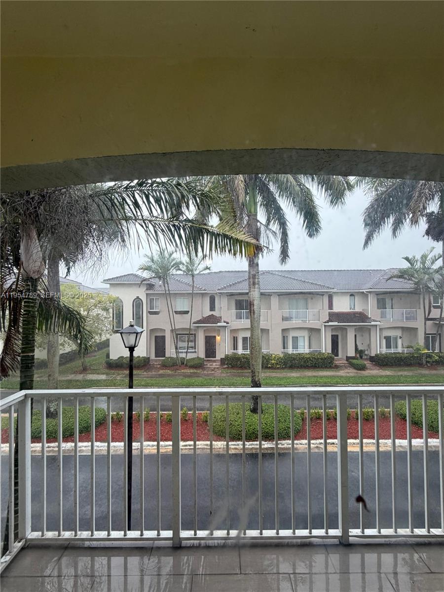 A view from a balcony overlooking a street, palm trees, and a multi-story residential building — 1948 SE 24th Ave, Homestead FL 33035, HOMESTEAD, FL