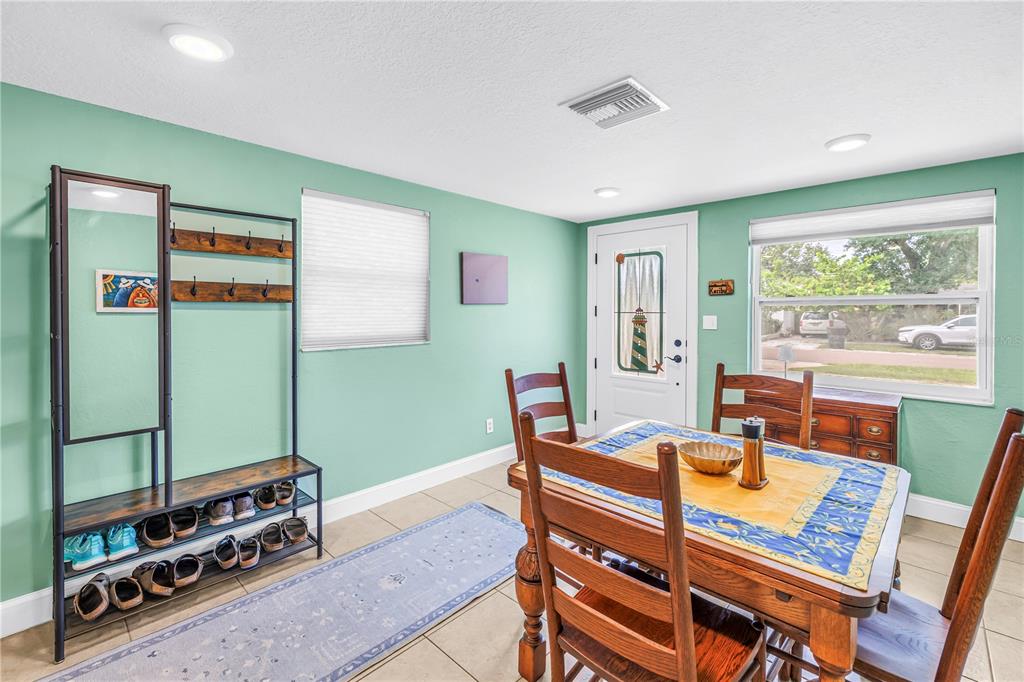 A dining area with light green walls, tile flooring, a wooden table, and a coat rack — 543 72ND AVE N, ST PETERSBURG, FL