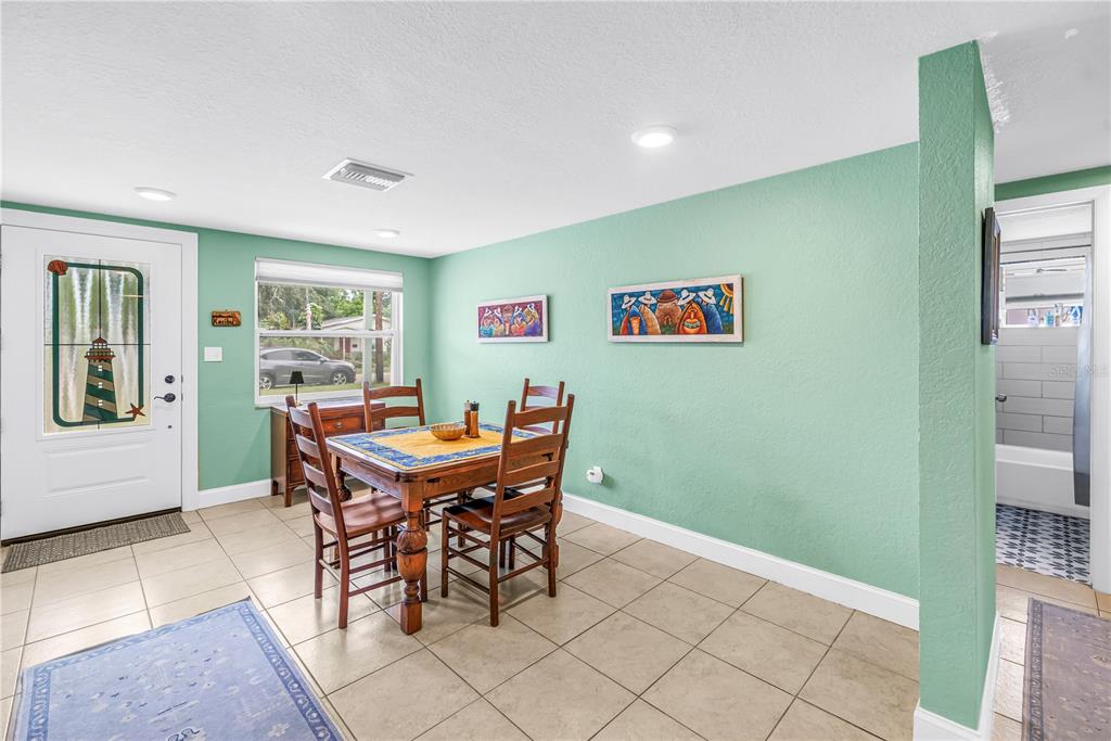 A dining area with tile floors, a wooden table, and light green walls — 543 72ND AVE N, ST PETERSBURG, FL