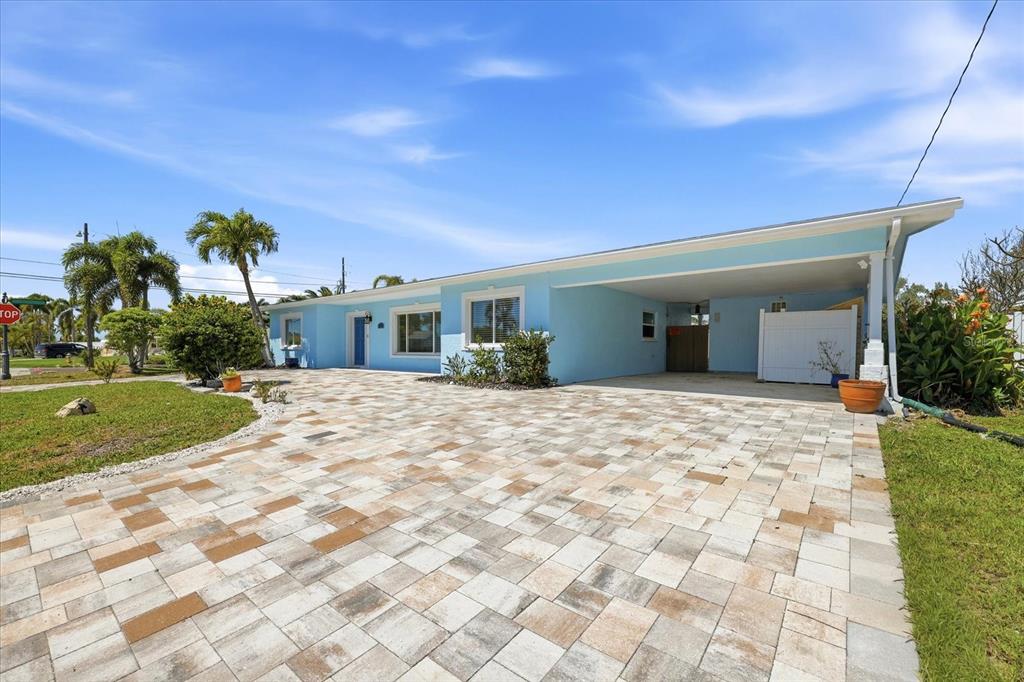A light blue single-story house features a large paver driveway and an attached carport — 7891 4TH AVENUE S, ST PETERSBURG, FL