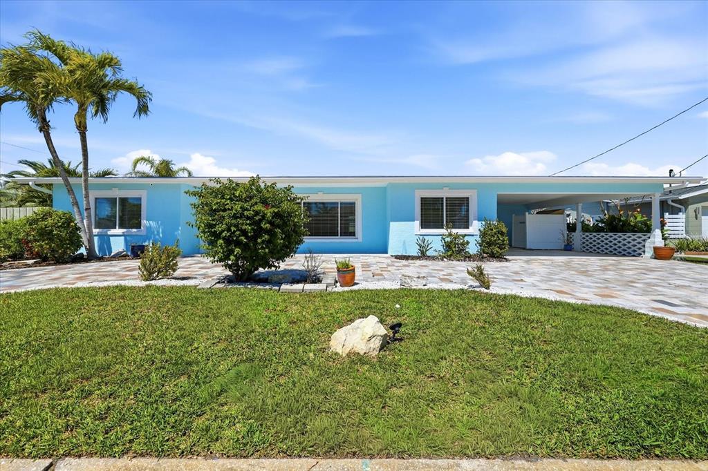 A light blue single-story house features a paved driveway, palm trees, and a carport — 7891 4TH AVENUE S, ST PETERSBURG, FL