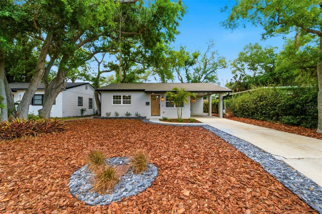 A single-story house with a light gray exterior, a wooden front door, and a carport — 8051 26TH AVENUE N, ST PETERSBURG, FL