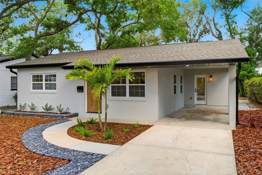 A single-story house with a light gray exterior, a carport, and a landscaped front yard — 8051 26TH AVENUE N, ST PETERSBURG, FL