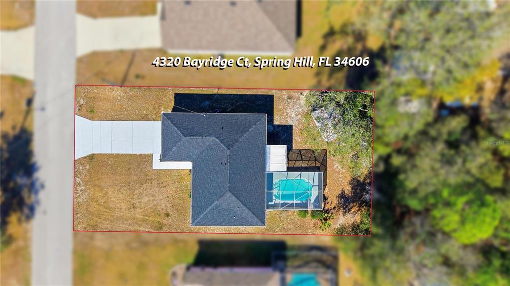 A single-story white house with a dark roof, garage, and front entrance sits on grass — 4320 BAYRIDGE COURT, SPRING HILL, FL