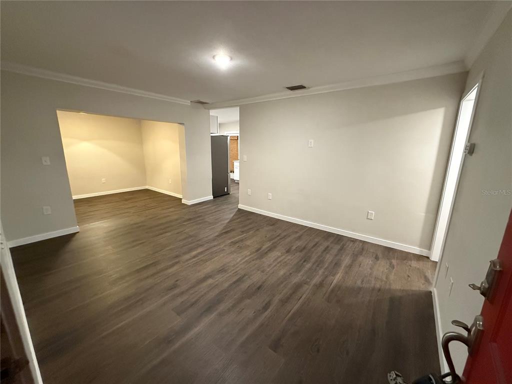 An interior view shows a living area with dark wood-look flooring and light gray walls — 6215 S KELLY ROAD, TAMPA, FL