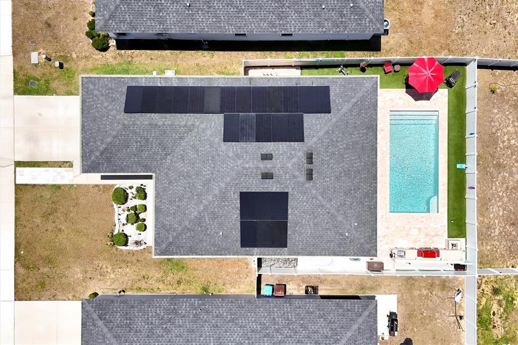 An aerial view of a house with solar panels, a swimming pool, and a backyard — 4055 RUBY RUN, HAINES CITY, FL