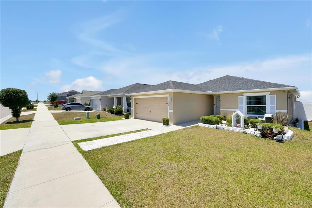 A single-story suburban house with a tan exterior, a two-car garage, and a front lawn — 4055 RUBY RUN, HAINES CITY, FL