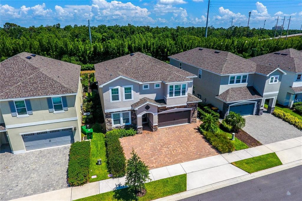 An aerial view shows three suburban houses with paved driveways and green lawns — 7463 MARKER AVENUE, KISSIMMEE, FL