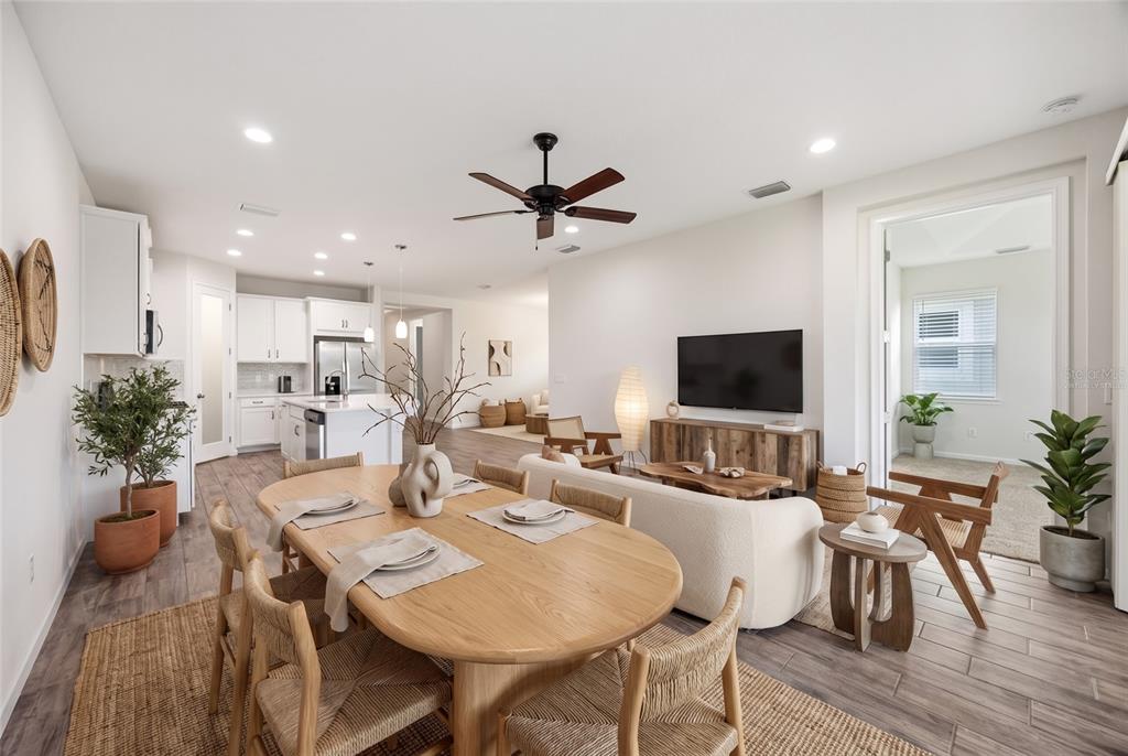 An open-concept living and dining area features light wood furniture, a neutral sofa, and kitchen — 8621 RAIN SONG ROAD, SARASOTA, FL