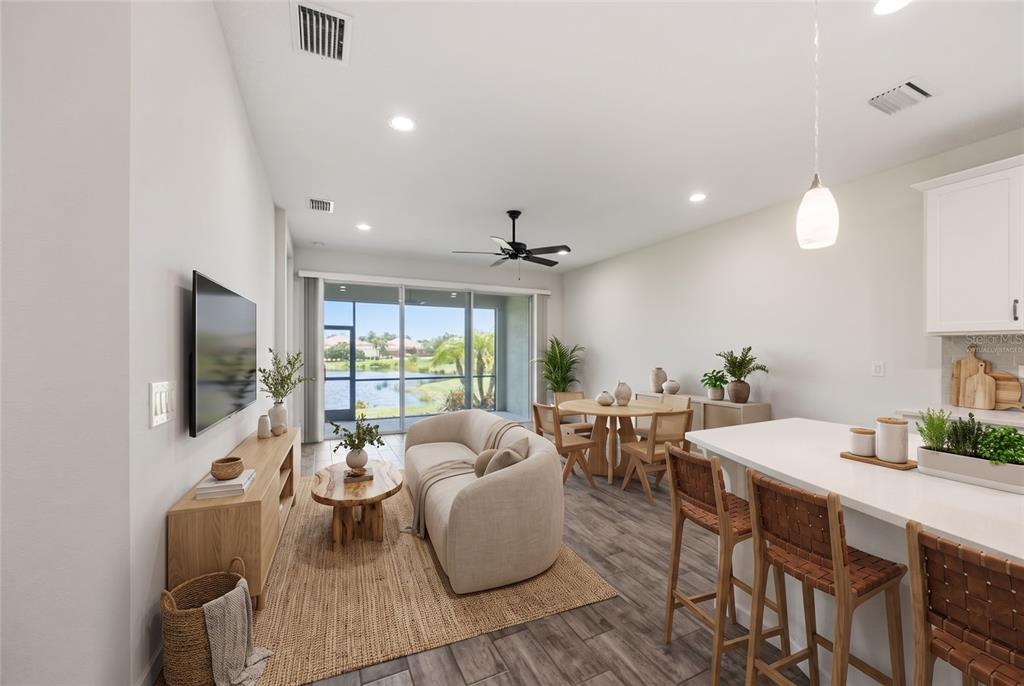 A living room and kitchen area with wood-look tile floors and a view of water — 8621 RAIN SONG ROAD, SARASOTA, FL