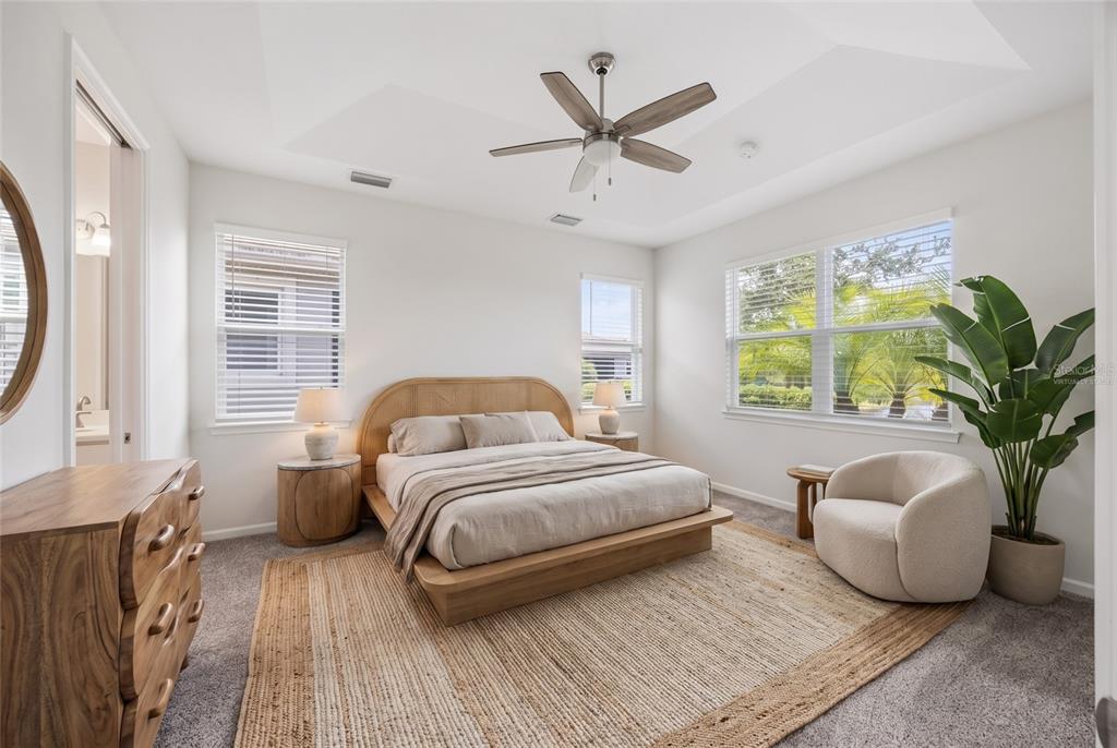 A bedroom features a wooden platform bed, a jute rug, and a curved armchair — 8621 RAIN SONG ROAD, SARASOTA, FL