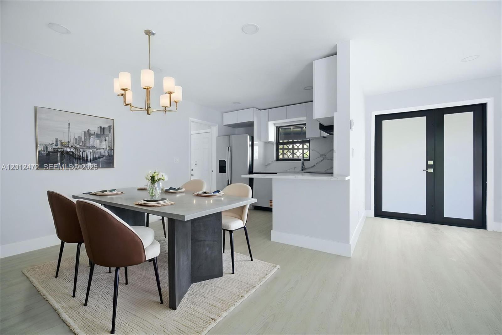 A dining area with a modern table and chairs sits adjacent to a white kitchen — 1930 NW 33rd St, Oakland Park FL 33309, OAKLAND PARK, FL