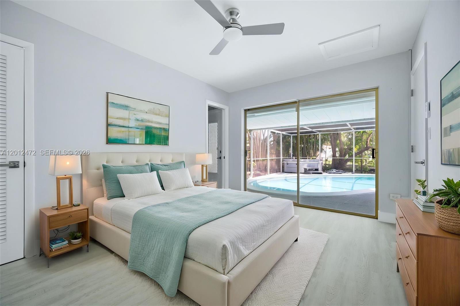 A bedroom features a bed, nightstands, and sliding glass doors overlooking a backyard swimming pool — 1930 NW 33rd St, Oakland Park FL 33309, OAKLAND PARK, FL