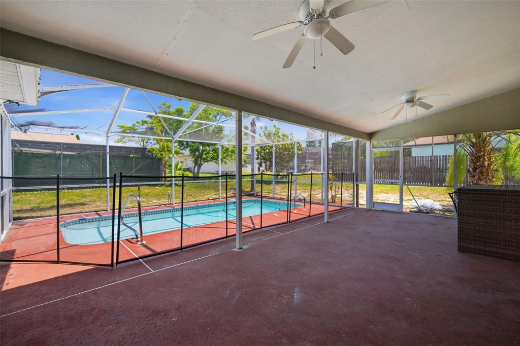 A covered patio with a ceiling fan overlooks a fenced swimming pool and backyard — 8316 SUMMERSIDE LANE, PORT RICHEY, FL