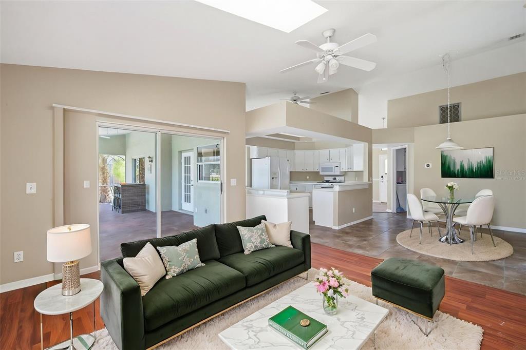 A living room with a green sofa, marble coffee table, and an adjacent dining area — 8316 SUMMERSIDE LANE, PORT RICHEY, FL