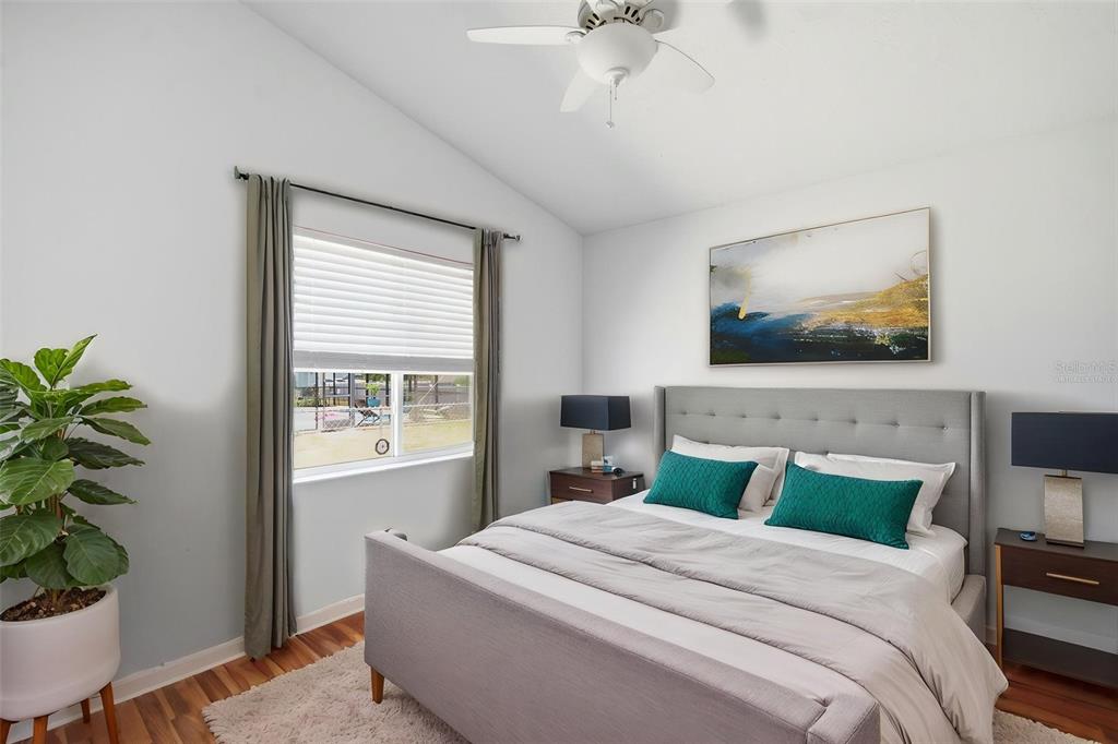 A bedroom features a gray upholstered bed, two nightstands, a ceiling fan, and a window — 8316 SUMMERSIDE LANE, PORT RICHEY, FL