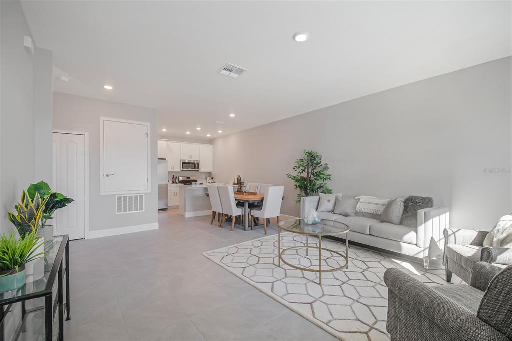 An open-concept living and dining area features light gray tile flooring and white cabinetry — 1748 CORIANDER DRIVE, KISSIMMEE, FL