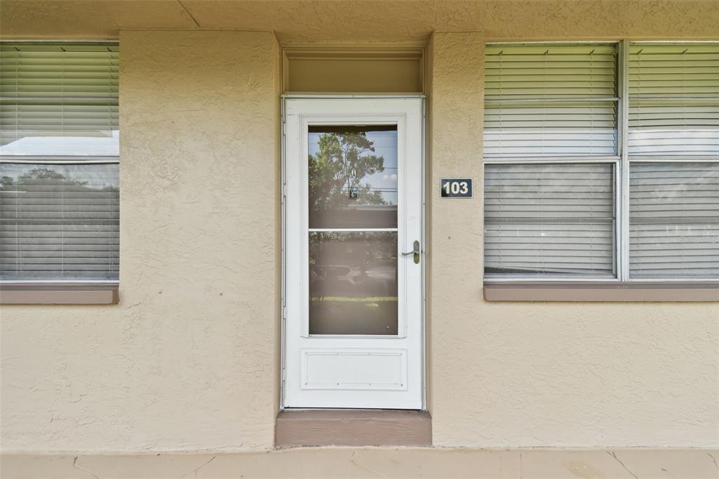 The exterior view shows a beige building entrance with a white storm door numbered 103 — 5095 BAY STREET NE UNIT 103, ST PETERSBURG, FL