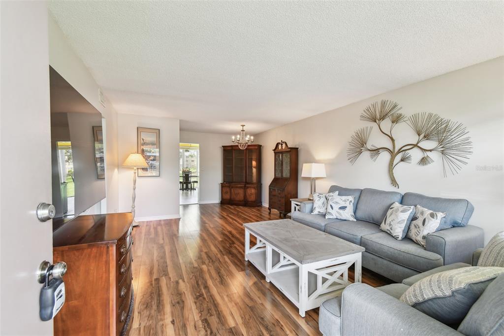 A living room features wood-look flooring, a gray sofa, a coffee table, and wall art — 5095 BAY STREET NE UNIT 103, ST PETERSBURG, FL