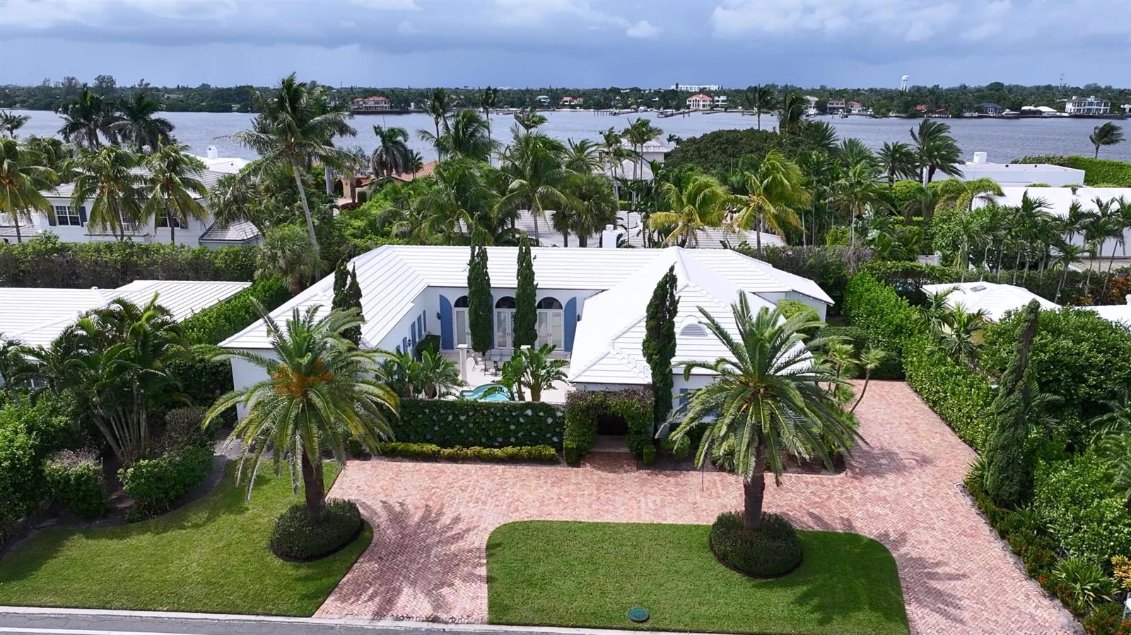 An aerial view shows a white house with a brick driveway, palm trees, and pool — 2258 E Ibis Isle Rd Road E, Palm Beach FL 33480, PALM BEACH, FL