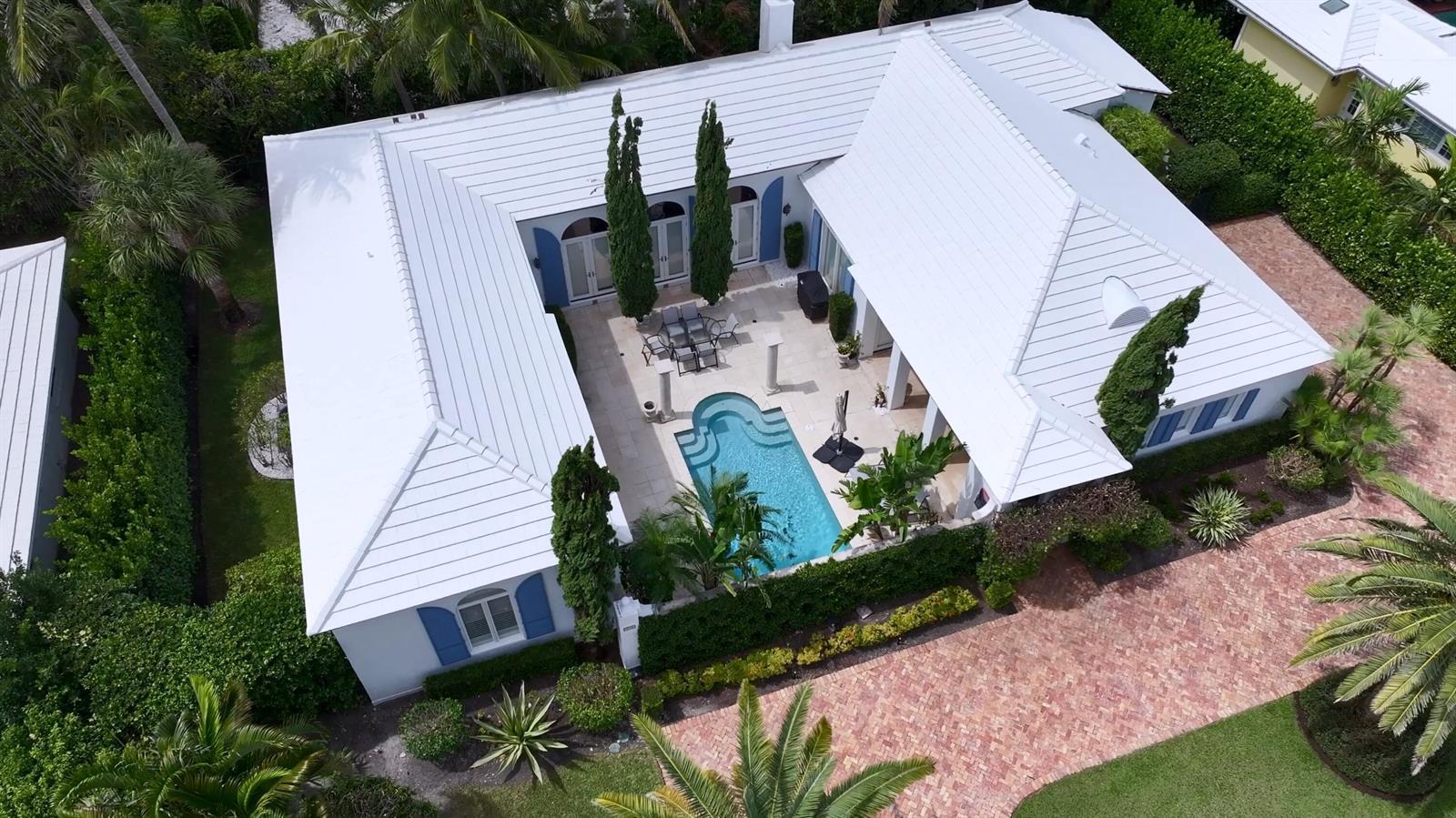 An aerial view of a U-shaped house with a white roof, courtyard pool, and patio — 2258 E Ibis Isle Rd Road E, Palm Beach FL 33480, PALM BEACH, FL