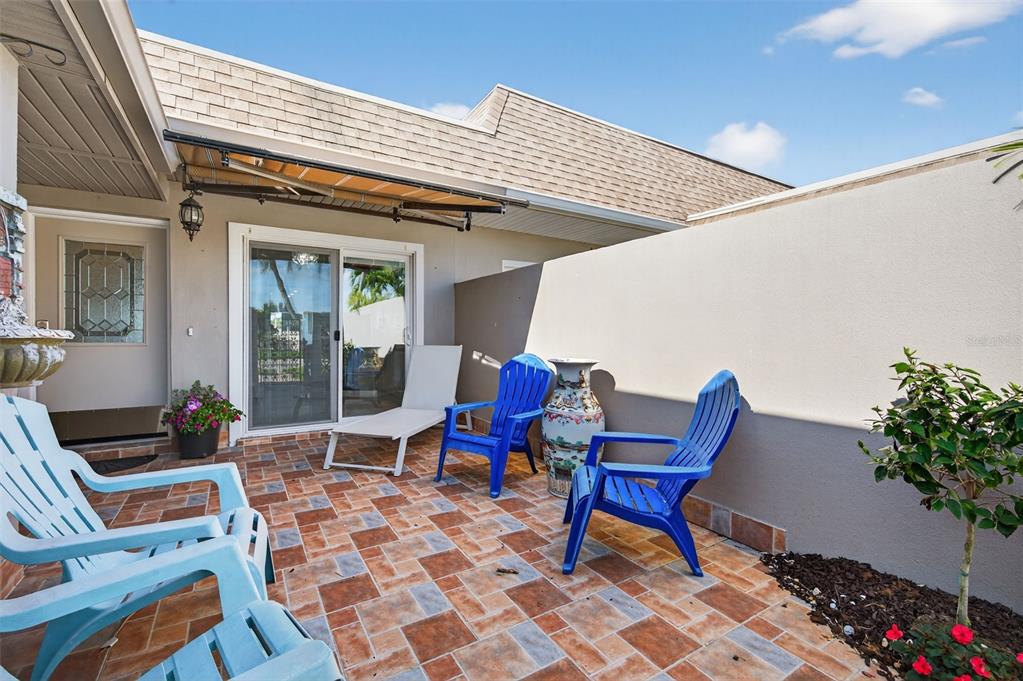 A patio features tiled flooring, blue chairs, a lounge chair, and a privacy wall — 427 BOCA CIEGA POINT BOULEVARD N, ST PETERSBURG, FL