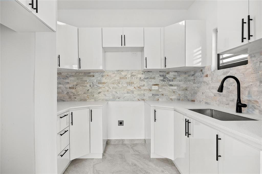 A kitchen features white cabinets, a stone tile backsplash, and a black faucet — 107 ESPERANZA, LUQUILLO, PR