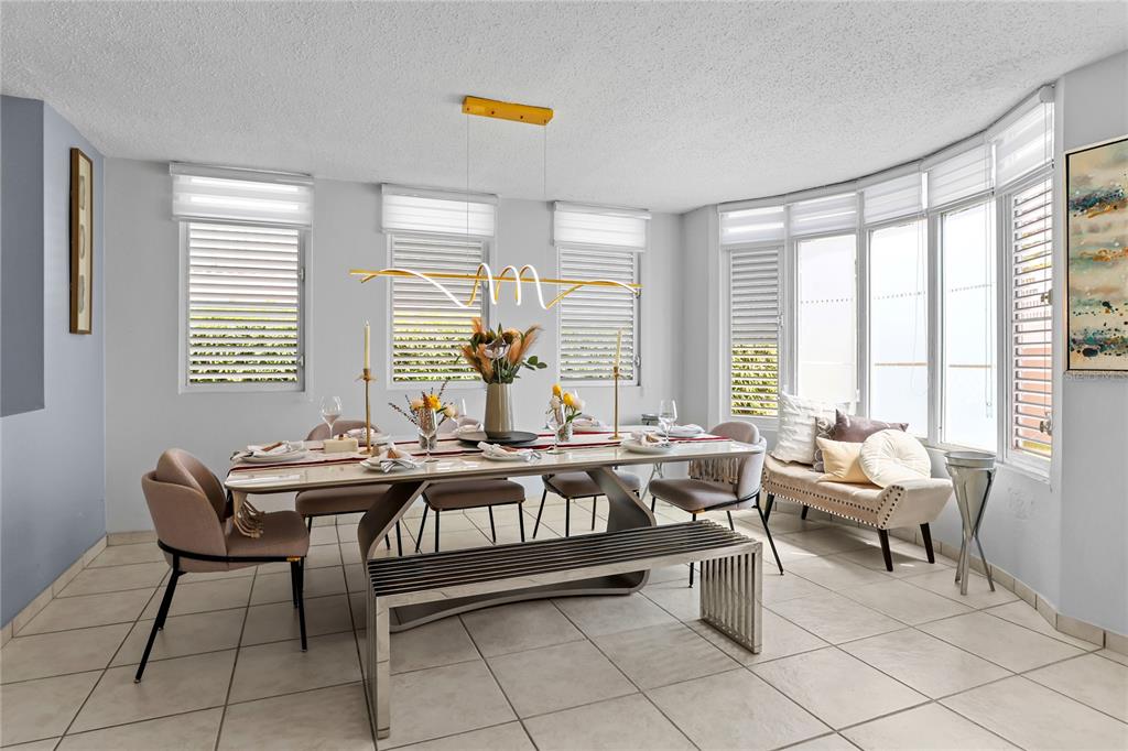 A dining room with a long table, modern light fixture, and a windowed seating area — 59 VIA SOL, CAGUAS, PR