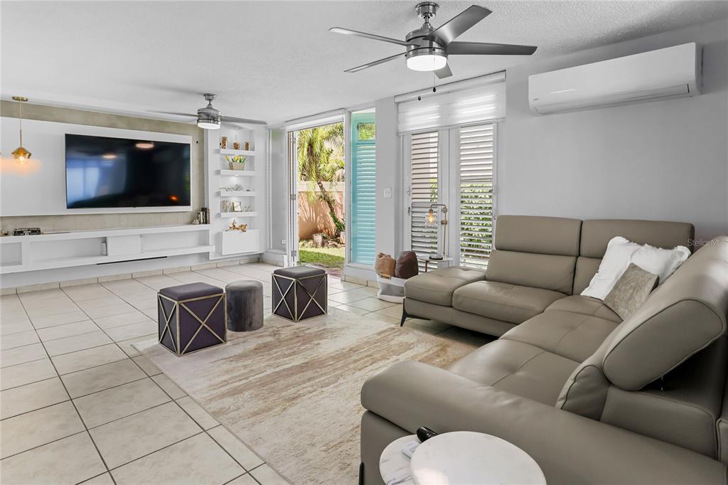 A living room features a large television, a sectional sofa, tile floors, and glass doors — 59 VIA SOL, CAGUAS, PR