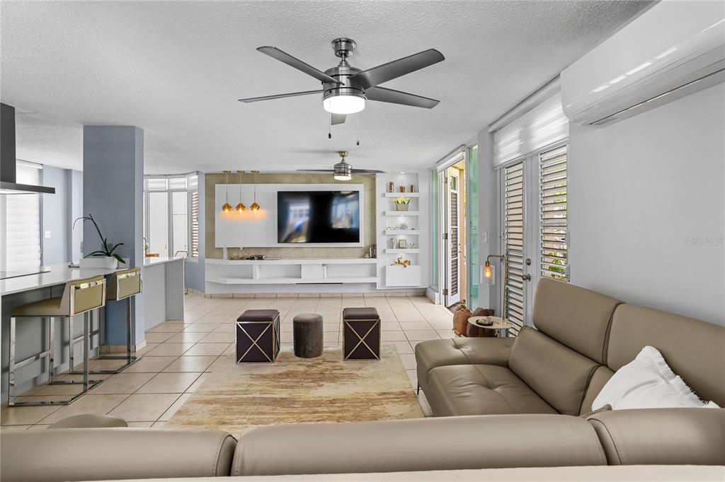 A modern living room features a large sectional sofa, a wall-mounted television, and tile flooring — 59 VIA SOL, CAGUAS, PR