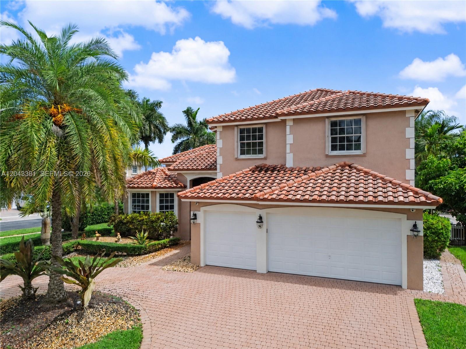 A two-story house with a terracotta tile roof, white garage doors, and a brick driveway — 18900 SW 32nd Ct, Miramar FL 33029, MIRAMAR, FL