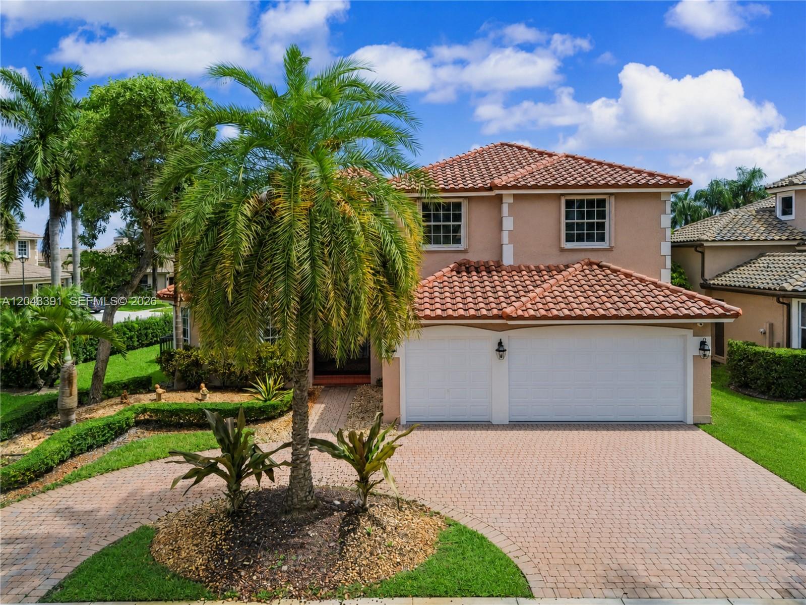 A two-story house with a tiled roof, white garage doors, and a palm tree out front — 18900 SW 32nd Ct, Miramar FL 33029, MIRAMAR, FL