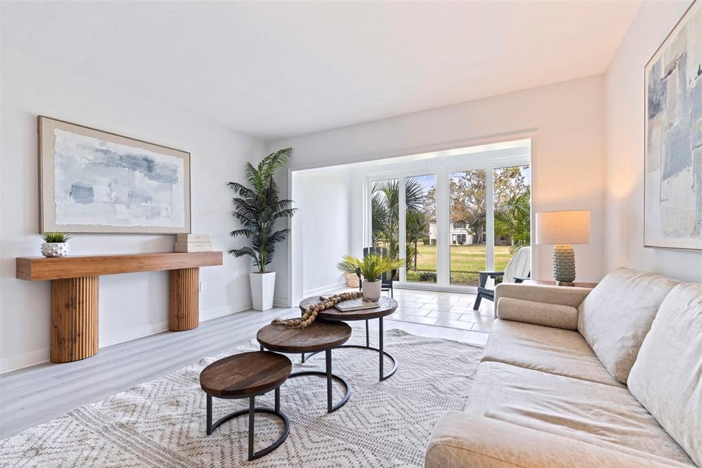 A living room features a beige sofa, nested wooden coffee tables, and large glass doors — 4480 OVERLOOK DRIVE NE UNIT 12, ST PETERSBURG, FL
