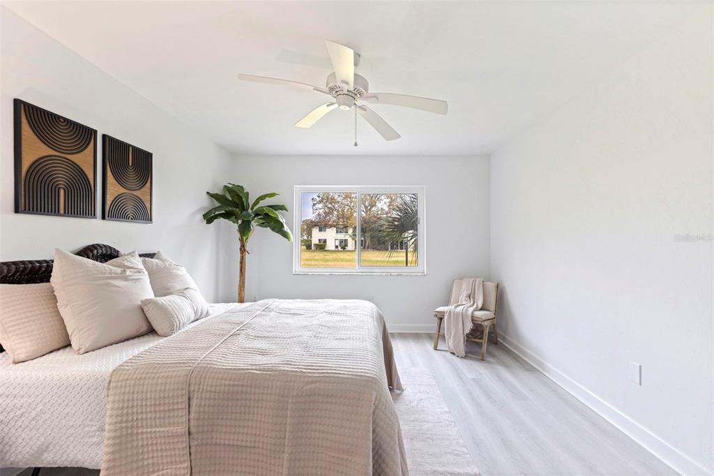 A bedroom features a bed, a ceiling fan, a potted plant, and a window view — 4480 OVERLOOK DRIVE NE UNIT 12, ST PETERSBURG, FL