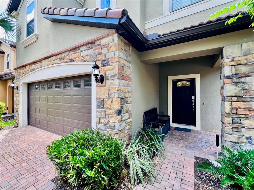 The exterior of a house features a stone-accented facade, a garage, and a front entrance — 2112 MOROCCO WAY, KISSIMMEE, FL
