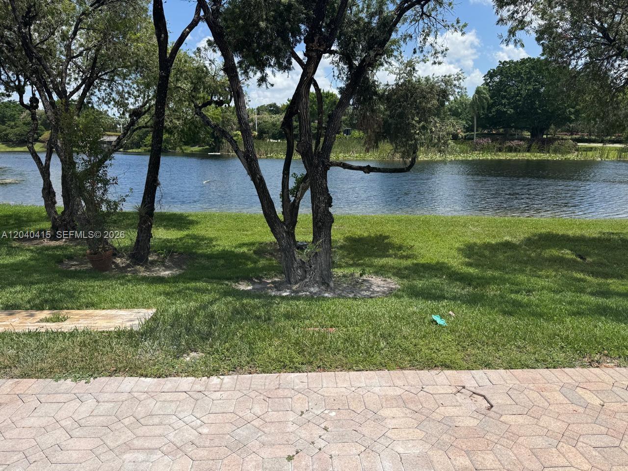 A view of a grassy lawn and trees overlooking a lake from a paved patio — 2360 Dover, Weston FL 33326, WESTON, FL