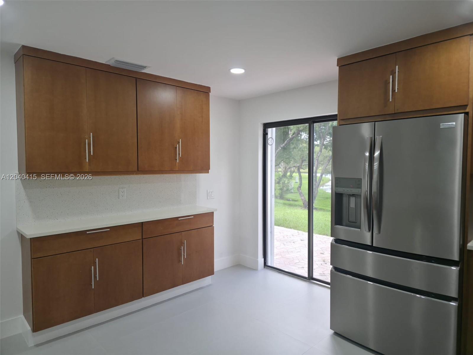 A kitchen features wood cabinets, white countertops, stainless steel appliances, and a sliding glass door — 2360 Dover, Weston FL 33326, WESTON, FL