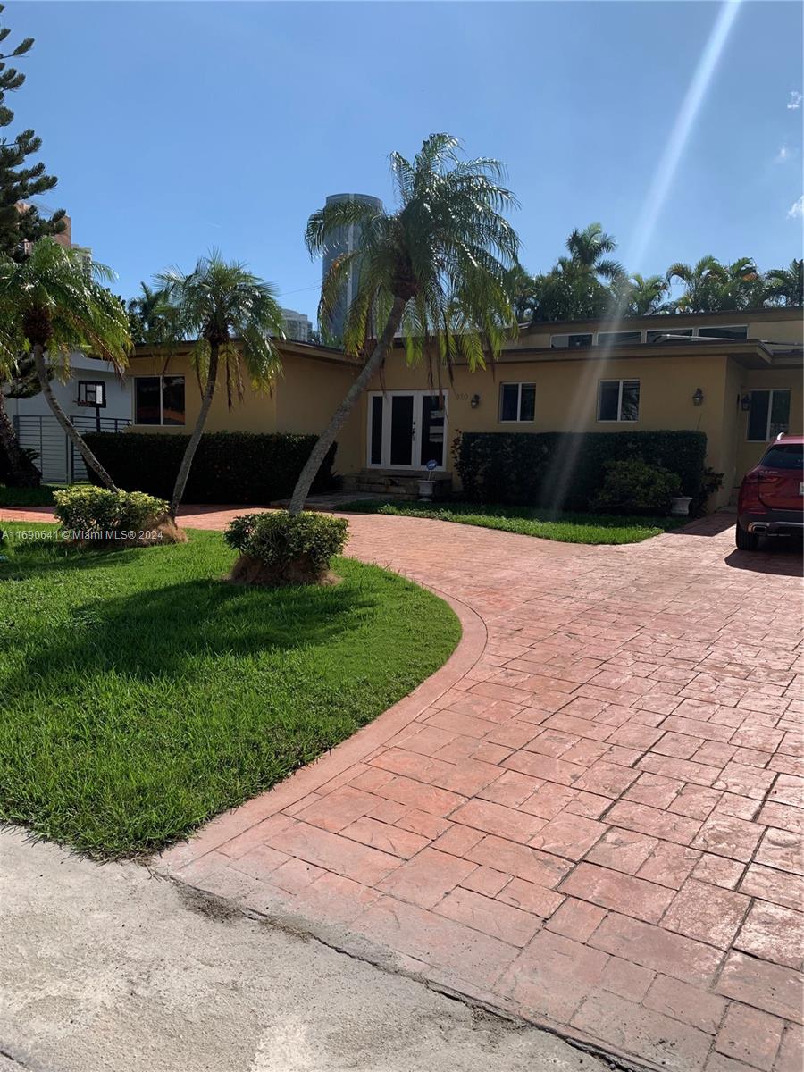 A single-story house with a paved driveway, palm trees, and a green lawn — 310 191st Ter, Sunny Isles Beach FL 33160, SUNNY ISLES BEACH, FL