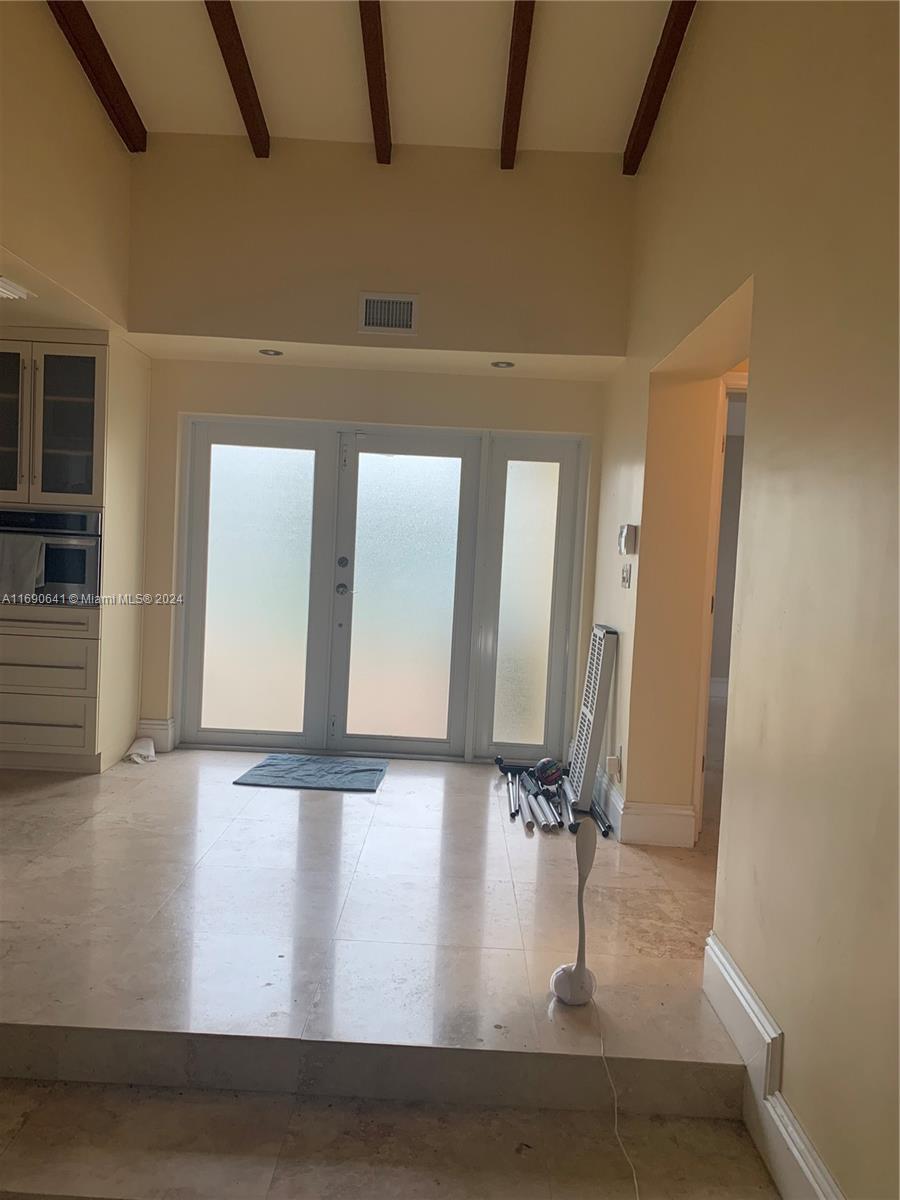 A room with a raised floor, vaulted ceiling with exposed beams, and glass double doors — 310 191st Ter, Sunny Isles Beach FL 33160, SUNNY ISLES BEACH, FL
