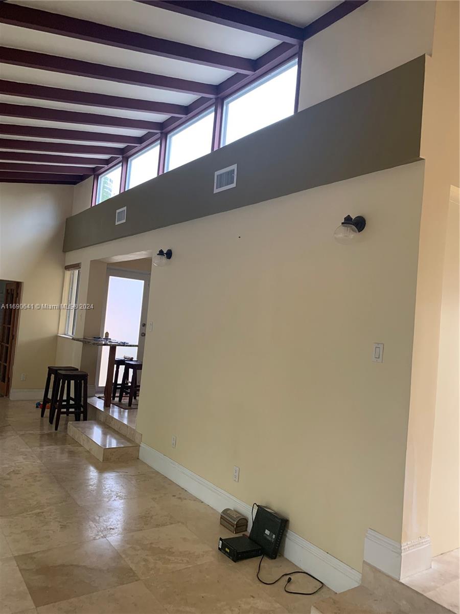 A living area features vaulted ceilings with exposed beams, clerestory windows, and stone flooring — 310 191st Ter, Sunny Isles Beach FL 33160, SUNNY ISLES BEACH, FL