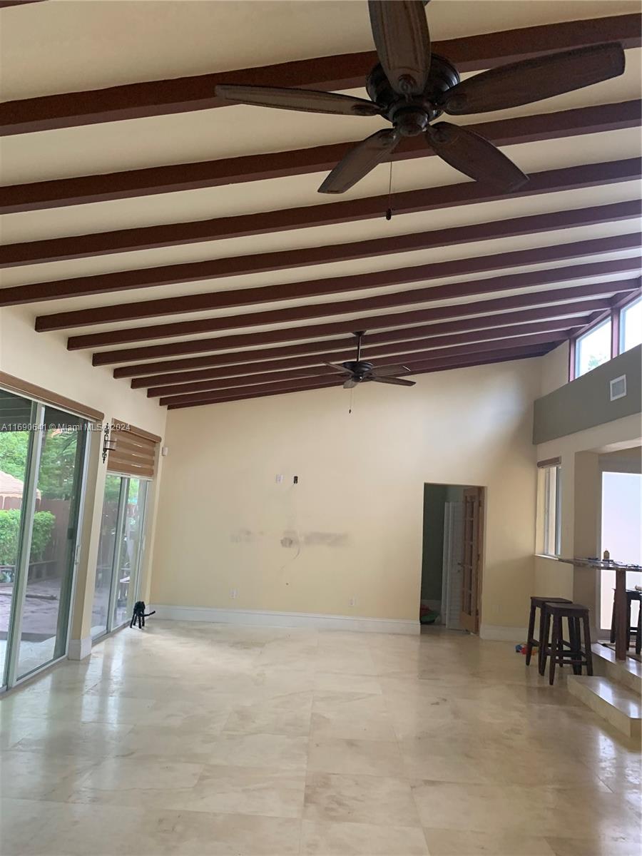 A spacious living room features a vaulted ceiling with exposed wooden beams and tile flooring — 310 191st Ter, Sunny Isles Beach FL 33160, SUNNY ISLES BEACH, FL