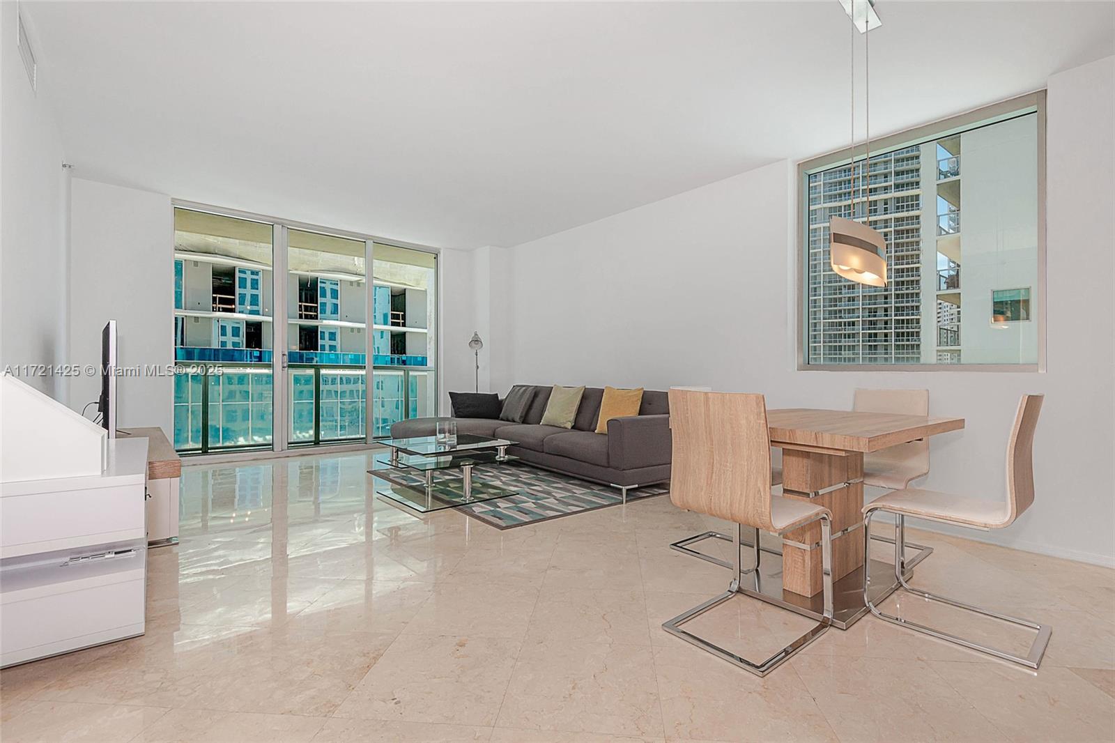 A modern living and dining area with tile floors, a gray sofa, and floor-to-ceiling windows — 55 SE 6th St # 1507, Miami FL 33131, MIAMI, FL