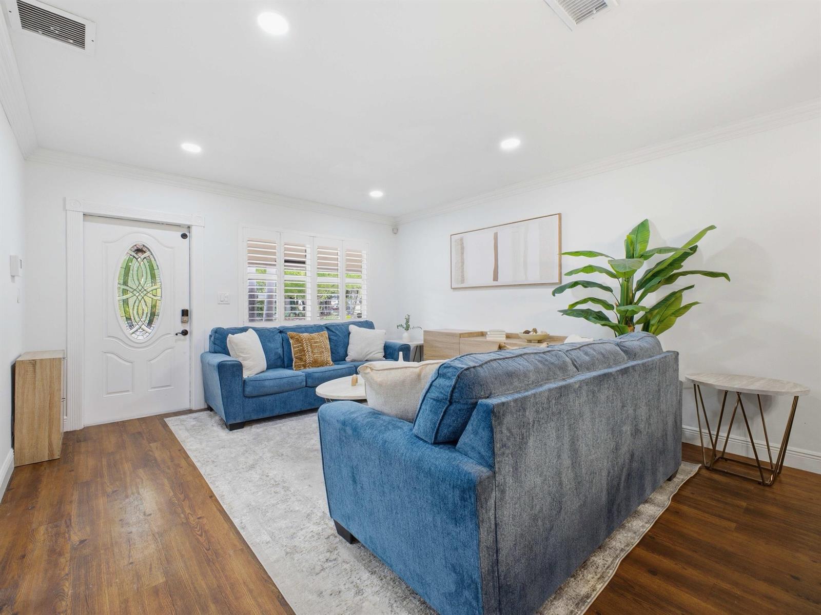 A living room features two blue sofas, a light rug, and wood-look flooring — 5120 NE 22nd Avenue, Lighthouse Point FL 33064, LIGHTHOUSE POINT, FL