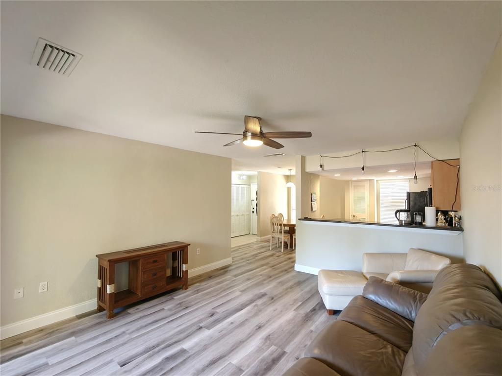 A living room with wood-look flooring, a ceiling fan, and a view into the dining area — 1810 NW 23RD BOULEVARD UNIT 165, GAINESVILLE, FL