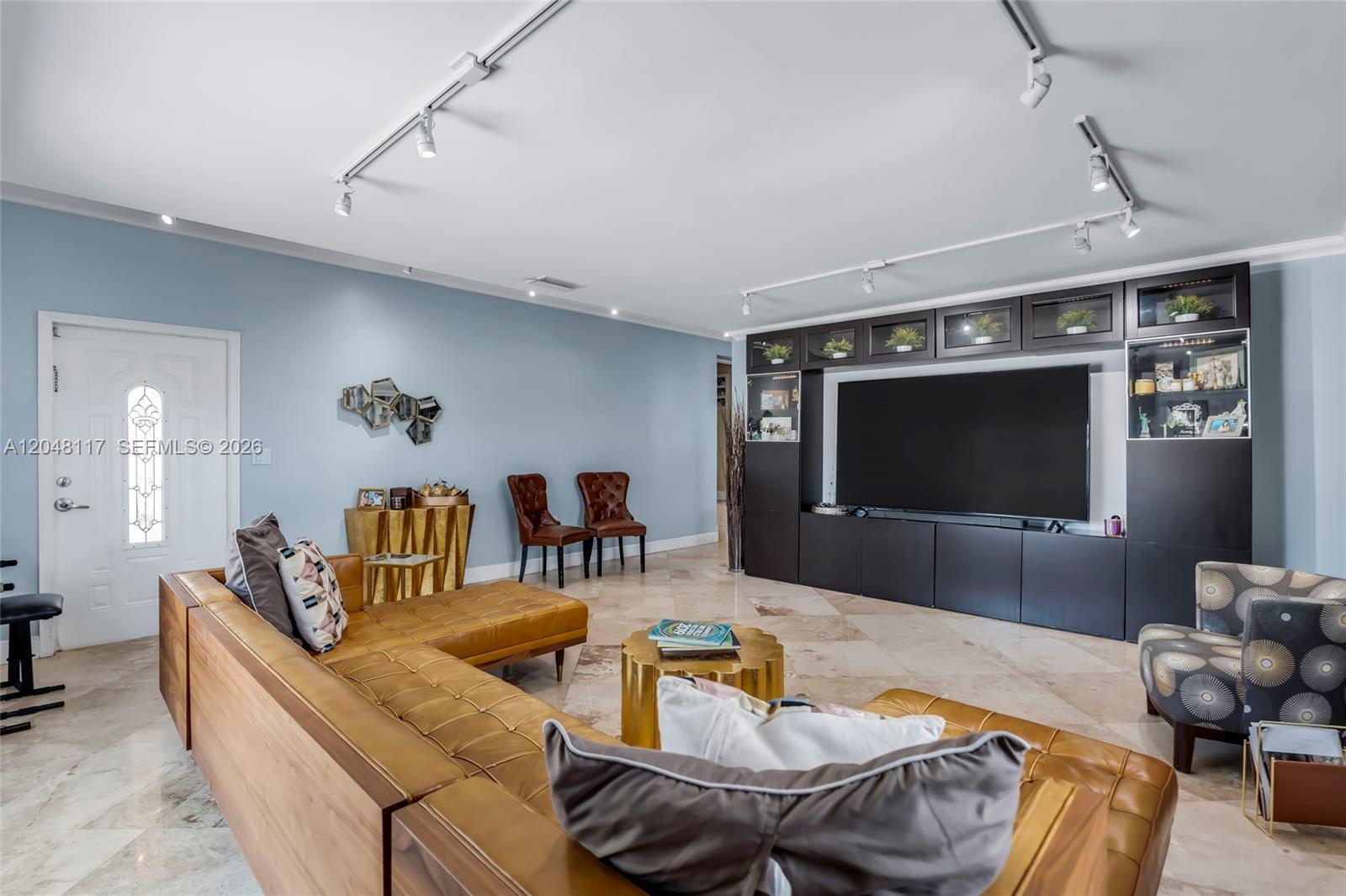 A living room features a large leather sectional, a dark entertainment center, and light blue walls — 114 SW SW 57th Ct, Miami FL 33144, MIAMI, FL