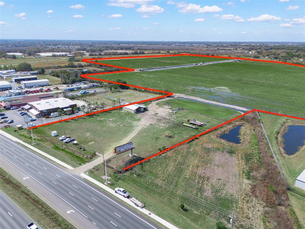 An aerial view shows a large plot of land outlined in red near a highway — US HIGHWAY 27, HAINES CITY, FL