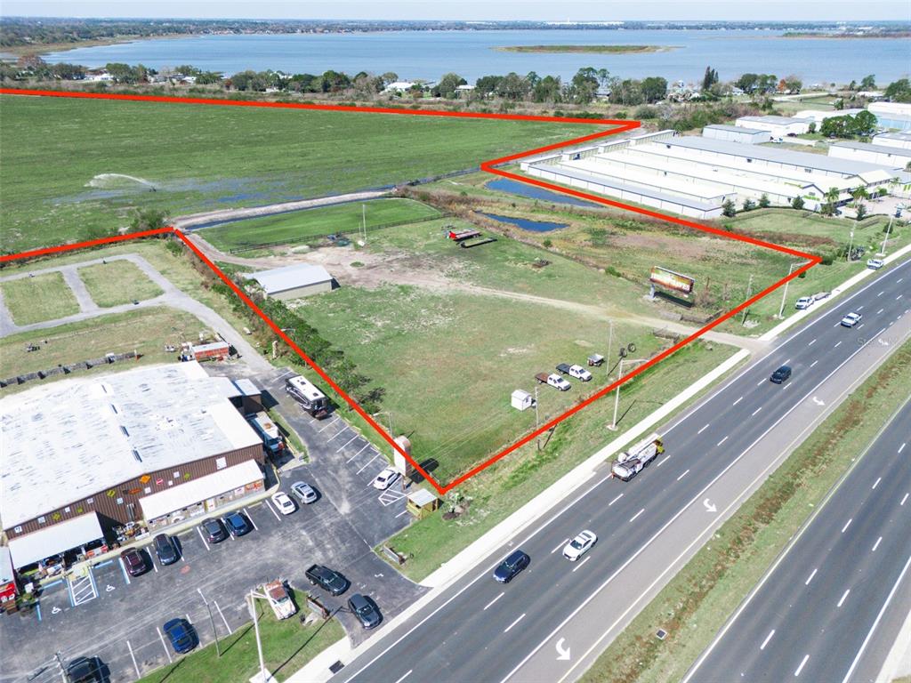 An aerial view shows a vacant lot outlined in red next to a highway — US HIGHWAY 27, HAINES CITY, FL